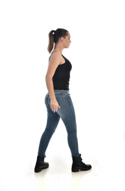 Tam boy siyah tek ve kot giyen esmer kız portresi. ayakta poz, yan profil. beyaz stüdyo arka plan üzerinde izole.