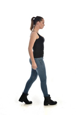 Tam boy siyah tek ve kot giyen esmer kız portresi. ayakta poz, yan profil. beyaz stüdyo arka plan üzerinde izole.