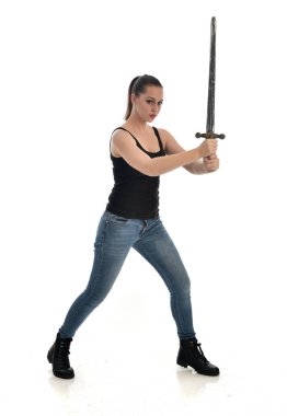 Tam boy siyah tek ve kot giyen esmer kız portresi. bir kılıç holding ayakta poz. beyaz stüdyo arka plan üzerinde izole.