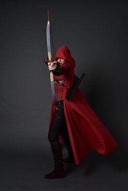 Tam boy esmer kız kırmızı Ortaçağ kostüm ve pelerin, ok ve yay tutarak portresi. gri studio arka plan üzerinde ayakta poz.