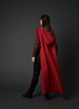 tam uzunlukta kırmızı Ortaçağ kostüm ve pelerin giymiş esmer kız portresi. ayakta poz ile kameranın arkasında gri studio arka plan.