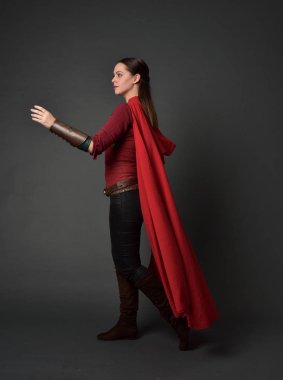 full length portrait of brunette girl wearing red medieval costume and cloak. standing pose   on grey studio background. clipart
