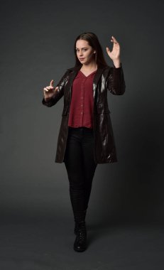 Tam boy esmer kız giyiyor kırmızı uzun deri jack portresi. gri studio arka plan üzerinde ayakta poz.