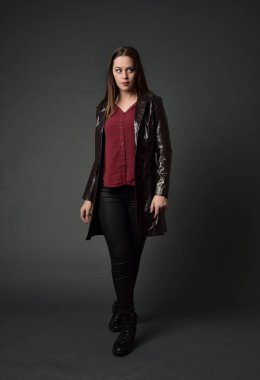 Tam boy esmer kız giyiyor kırmızı uzun deri jack portresi. gri studio arka plan üzerinde ayakta poz.