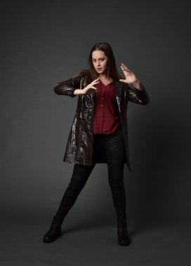 Tam boy esmer kız giyiyor kırmızı uzun deri jack portresi. gri studio arka plan üzerinde ayakta poz.