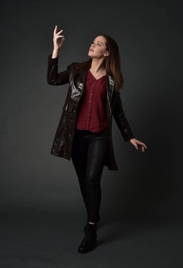 Tam boy esmer kız giyiyor kırmızı uzun deri jack portresi. gri studio arka plan üzerinde ayakta poz.