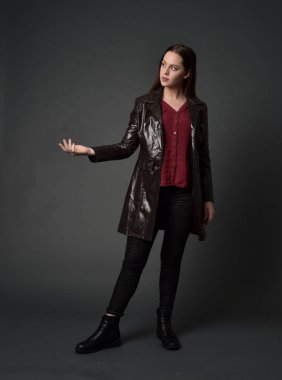 Tam boy esmer kız giyiyor kırmızı uzun deri jack portresi. gri studio arka plan üzerinde ayakta poz.