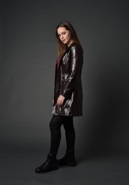 Tam boy esmer kız giyiyor kırmızı uzun deri jack portresi. gri studio arka plan üzerinde ayakta poz.