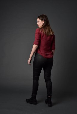 tam uzunlukta kırmızı gömlek ve deri pantolon giyen esmer kız portresi. gri studio arka plan üzerinde ayakta poz.