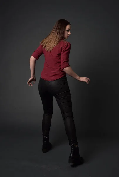 穿红色衬衫和皮裤的黑发女孩的全长肖像 站在姿势 在灰色的工作室背景 — 图库照片