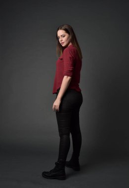 tam uzunlukta kırmızı gömlek ve deri pantolon giyen esmer kız portresi. gri studio arka plan üzerinde ayakta poz.