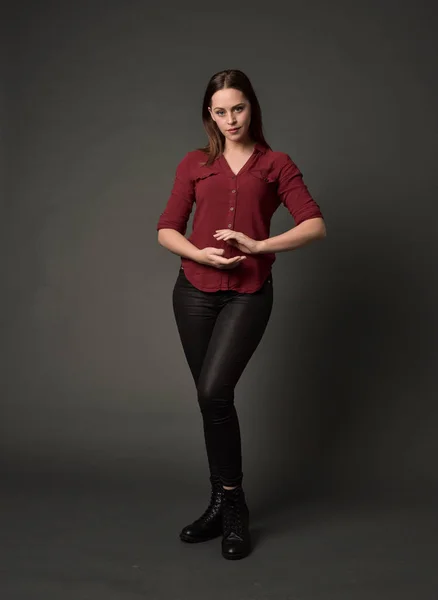 穿红色衬衫和皮裤的黑发女孩的全长肖像 站在姿势 在灰色的工作室背景 — 图库照片