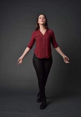 tam uzunlukta kırmızı gömlek ve deri pantolon giyen esmer kız portresi. gri studio arka plan üzerinde ayakta poz.
