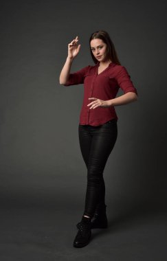 tam uzunlukta kırmızı gömlek ve deri pantolon giyen esmer kız portresi. gri studio arka plan üzerinde ayakta poz.