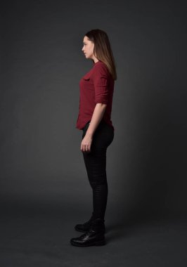 tam uzunlukta kırmızı gömlek ve deri pantolon giyen esmer kız portresi. gri studio arka plan üzerinde ayakta poz.