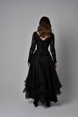 Tam boy esmer kız uzun siyah dantel elbise zekâ korse giymek portresi. ayakta poz geri gönderin. gri studio arka plan üzerinde izole.