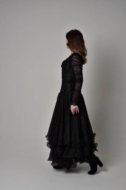 Tam boy esmer kız uzun siyah dantel elbise zekâ korse giymek portresi. ayakta poz geri gönderin. gri studio arka plan üzerinde izole.