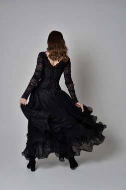 Tam boy esmer kız uzun siyah dantel elbise zekâ korse giymek portresi. ayakta poz geri gönderin. gri studio arka plan üzerinde izole.