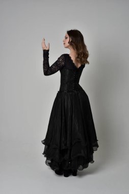 Tam boy esmer kız uzun siyah dantel elbise zekâ korse giymek portresi. ayakta poz geri gönderin. gri studio arka plan üzerinde izole.