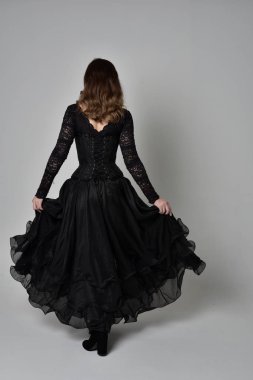 Tam boy esmer kız uzun siyah dantel elbise zekâ korse giymek portresi. ayakta poz geri gönderin. gri studio arka plan üzerinde izole.