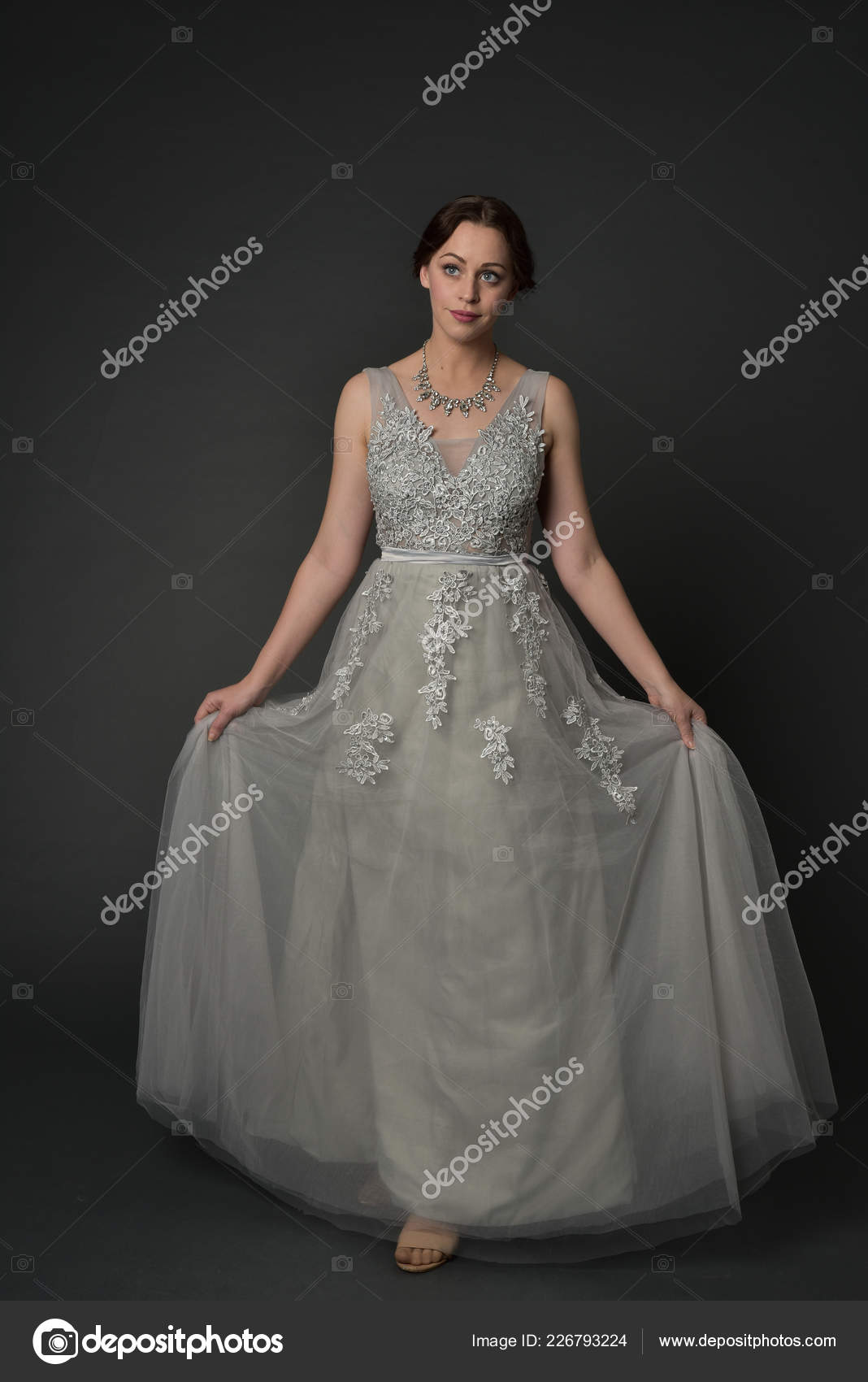 Elegant woman in blue ball gown dress standing and posing on a sunny evening  at city street. Fashion model full length portrait Stock Photo - Alamy