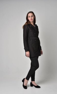 uzun, siyah ceket, gri studio arka plan üzerinde ayakta poz giyen bir esmer kız portresi tam uzunlukta.