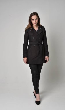 uzun, siyah ceket, gri studio arka plan üzerinde ayakta poz giyen bir esmer kız portresi tam uzunlukta.