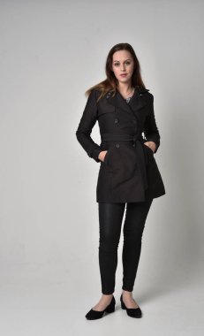 uzun, siyah ceket, gri studio arka plan üzerinde ayakta poz giyen bir esmer kız portresi tam uzunlukta.