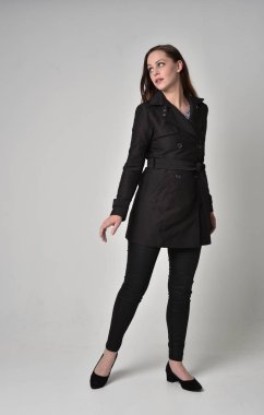 uzun, siyah ceket, gri studio arka plan üzerinde ayakta poz giyen bir esmer kız portresi tam uzunlukta.