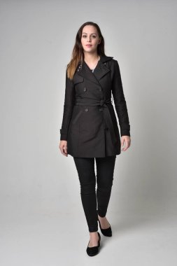 uzun, siyah ceket, gri studio arka plan üzerinde ayakta poz giyen bir esmer kız portresi tam uzunlukta.