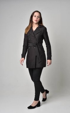 uzun, siyah ceket, gri studio arka plan üzerinde ayakta poz giyen bir esmer kız portresi tam uzunlukta.
