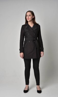 uzun, siyah ceket, gri studio arka plan üzerinde ayakta poz giyen bir esmer kız portresi tam uzunlukta.