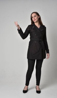 uzun, siyah ceket, gri studio arka plan üzerinde ayakta poz giyen bir esmer kız portresi tam uzunlukta.