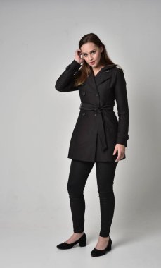 uzun, siyah ceket, gri studio arka plan üzerinde ayakta poz giyen bir esmer kız portresi tam uzunlukta.