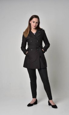 uzun, siyah ceket, gri studio arka plan üzerinde ayakta poz giyen bir esmer kız portresi tam uzunlukta.