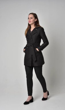 uzun, siyah ceket, gri studio arka plan üzerinde ayakta poz giyen bir esmer kız portresi tam uzunlukta.