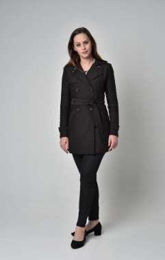 uzun, siyah ceket, gri studio arka plan üzerinde ayakta poz giyen bir esmer kız portresi tam uzunlukta.