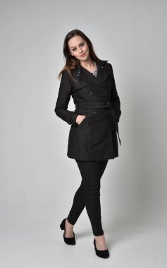 uzun, siyah ceket, gri studio arka plan üzerinde ayakta poz giyen bir esmer kız portresi tam uzunlukta.