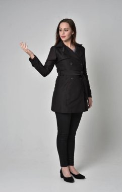 uzun, siyah ceket, gri studio arka plan üzerinde ayakta poz giyen bir esmer kız portresi tam uzunlukta.