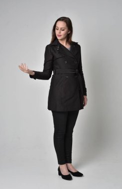 uzun, siyah ceket, gri studio arka plan üzerinde ayakta poz giyen bir esmer kız portresi tam uzunlukta.