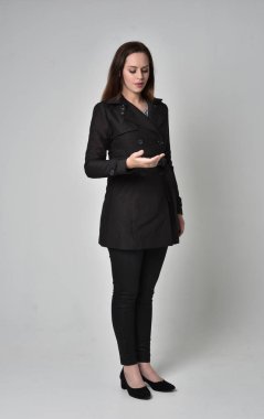 uzun, siyah ceket, gri studio arka plan üzerinde ayakta poz giyen bir esmer kız portresi tam uzunlukta.