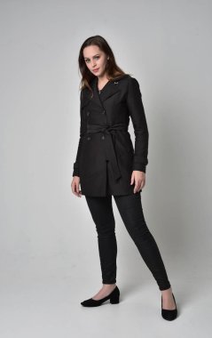 uzun, siyah ceket, gri studio arka plan üzerinde ayakta poz giyen bir esmer kız portresi tam uzunlukta.