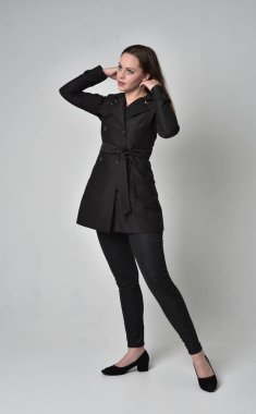 uzun, siyah ceket, gri studio arka plan üzerinde ayakta poz giyen bir esmer kız portresi tam uzunlukta.