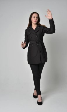 uzun, siyah ceket, gri studio arka plan üzerinde ayakta poz giyen bir esmer kız portresi tam uzunlukta.