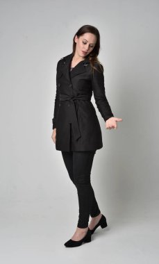 uzun, siyah ceket, gri studio arka plan üzerinde ayakta poz giyen bir esmer kız portresi tam uzunlukta.