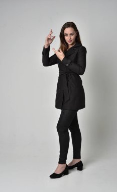 uzun, siyah ceket, gri studio arka plan üzerinde ayakta poz giyen bir esmer kız portresi tam uzunlukta.