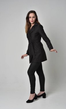 uzun, siyah ceket, gri studio arka plan üzerinde ayakta poz giyen bir esmer kız portresi tam uzunlukta.
