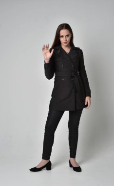 uzun, siyah ceket, gri studio arka plan üzerinde ayakta poz giyen bir esmer kız portresi tam uzunlukta.