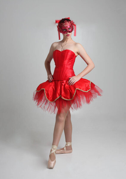 портрет девушки в красной балетной пачке и маске. танцевальная поза на фоне студии
.