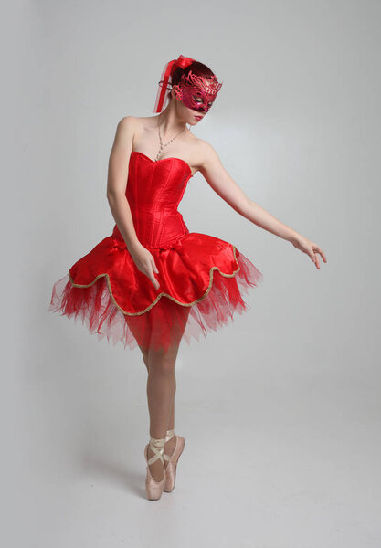 портрет девушки в красной балетной пачке и маске. танцевальная поза на фоне студии
.